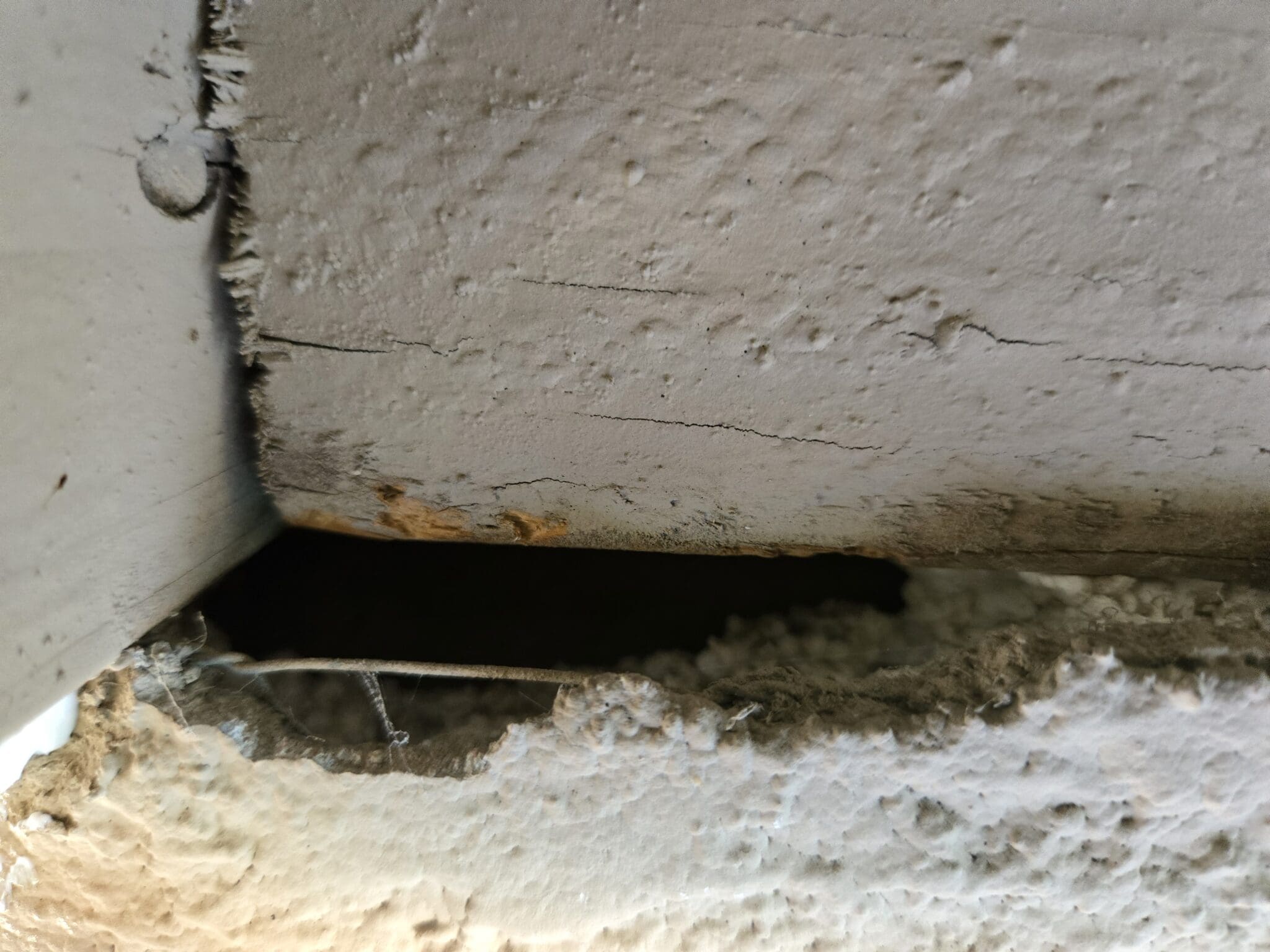 A small rectangular hole in a rough concrete wall.