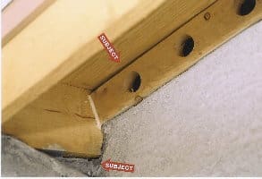 Close-up of a wooden structure with holes and labels.