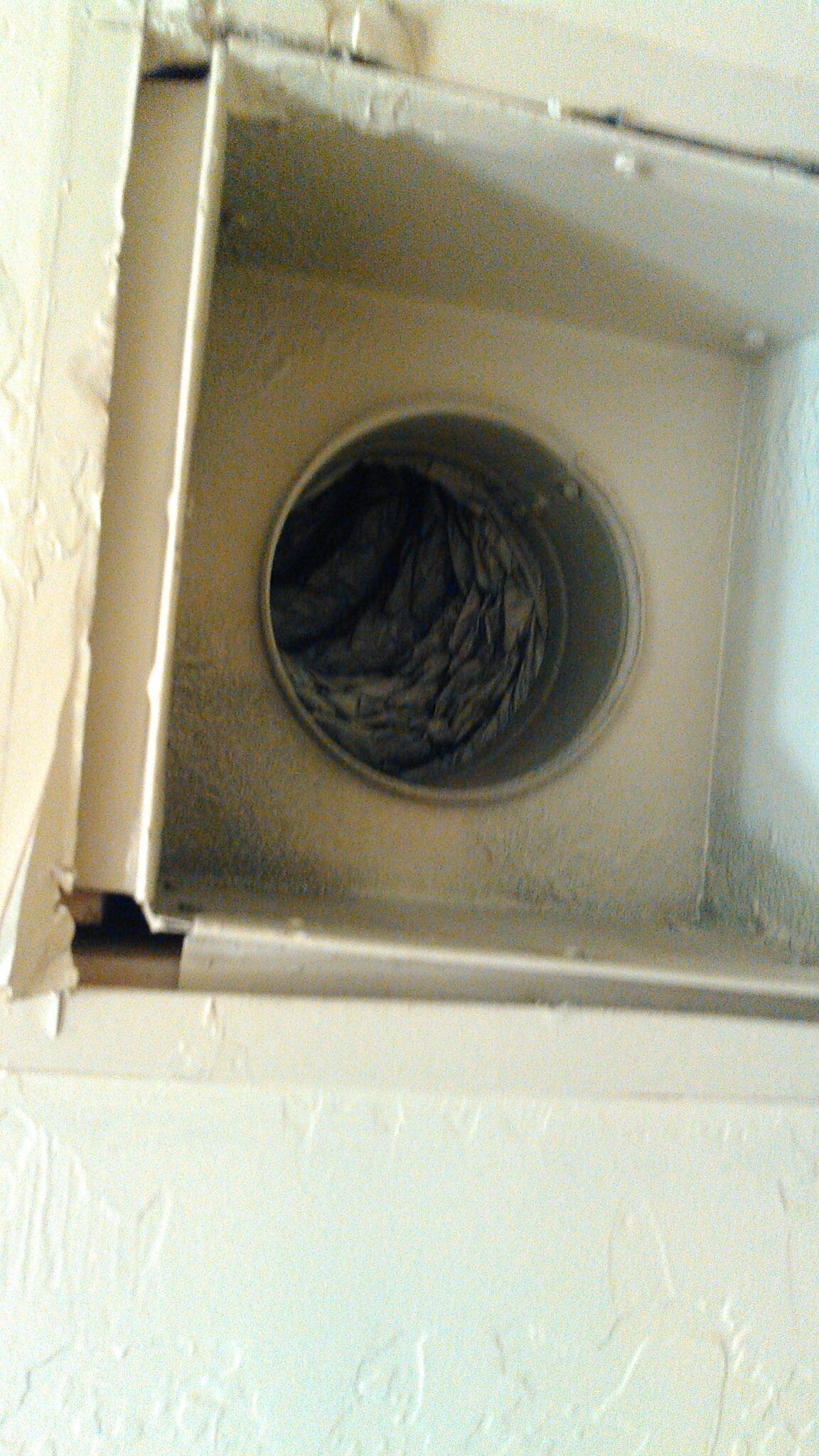 Dusty dryer vent with lint buildup inside.