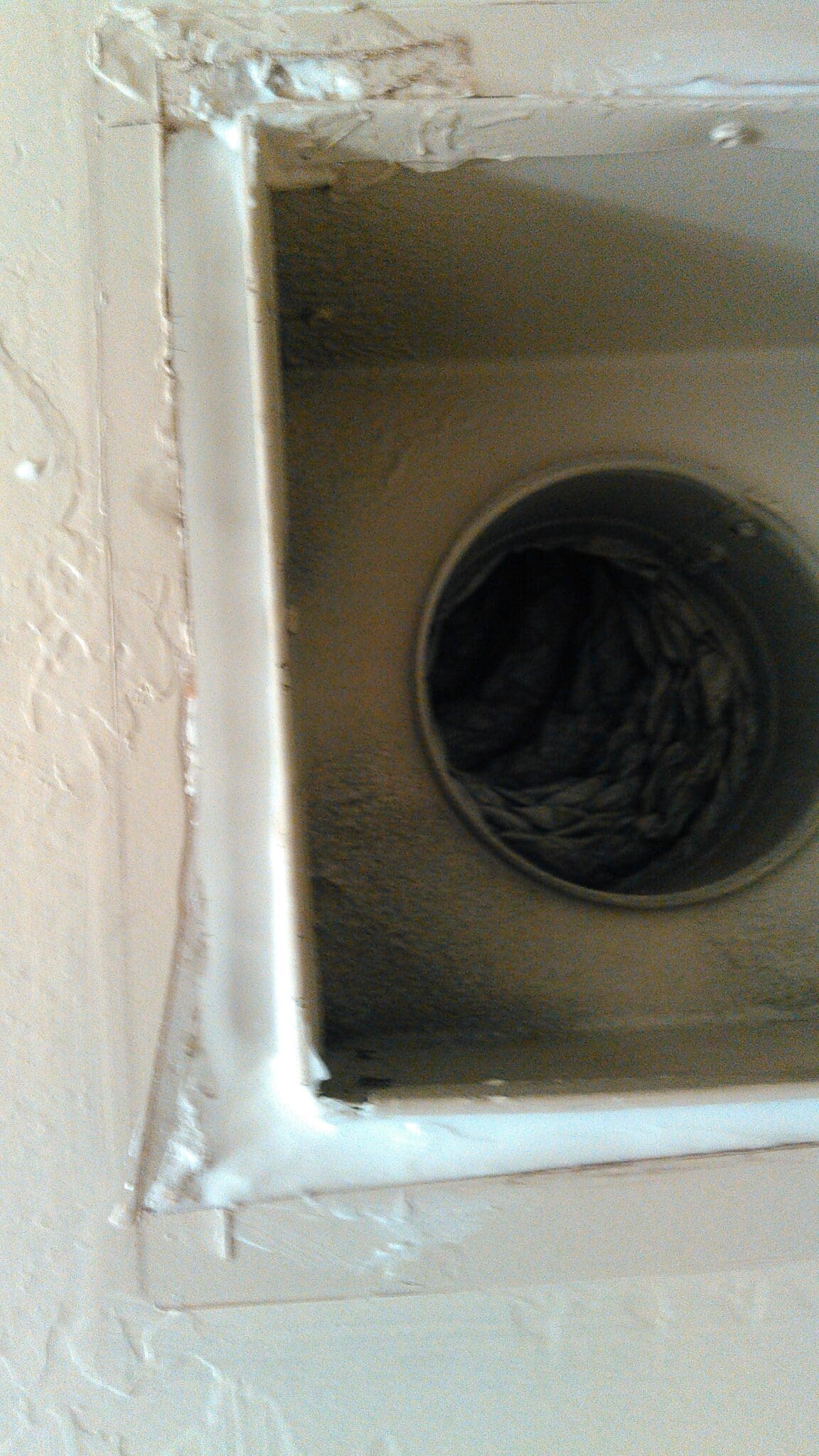 Close-up of a dusty and dirty air vent inside a household appliance.
