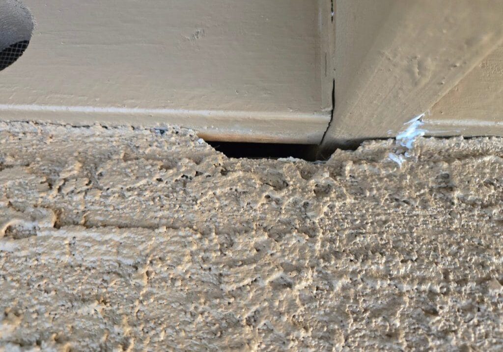 Close up of a gap between a concrete floor and a door frame.