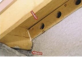 Close-up of a wooden structure with holes and labels.