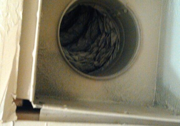 Dusty dryer vent with lint buildup inside.