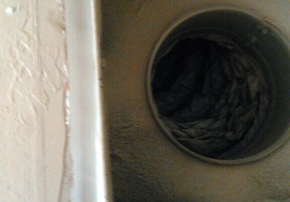 Close-up of a dusty and dirty air vent inside a household appliance.